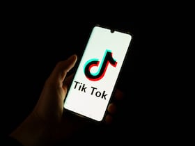 Cette photographie prise le 19 avril 2024 montre un homme tenant un smartphone affichant le logo de la plateforme de médias sociaux chinoise Tiktok dans un bureau à Paris.