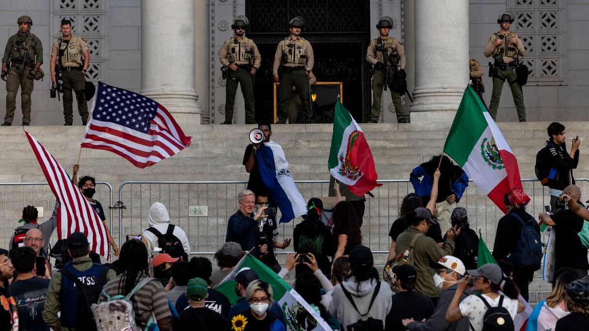 Des adjoints du shérif montent la garde alors que les manifestants se rassemblent sur les marches de l'hôtel de ville en réponse aux opérations d'immigration fédérales à Los Angeles le 13 juin 2025