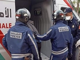 Trois agents de police font entrer une personne dans une fourgonnette de la Sûreté Nationale, au Maroc.
