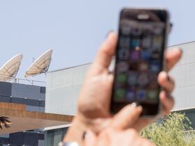 Une femme utilise son iPhone devant le bâtiment abritant le groupe israélien NSO, à Herzliya, près de Tel Aviv. L'entreprise israélienne est accusée d'avoir fourni le logiciel espion Pegasus à plusieurs Etats, dont le Maroc (photo d'archives, 2016).