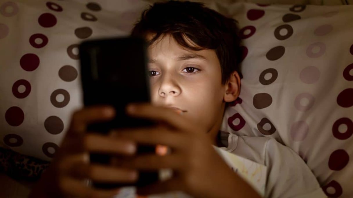 Un jeune adolescent sur son smartphone. Photographie d'illustration.
