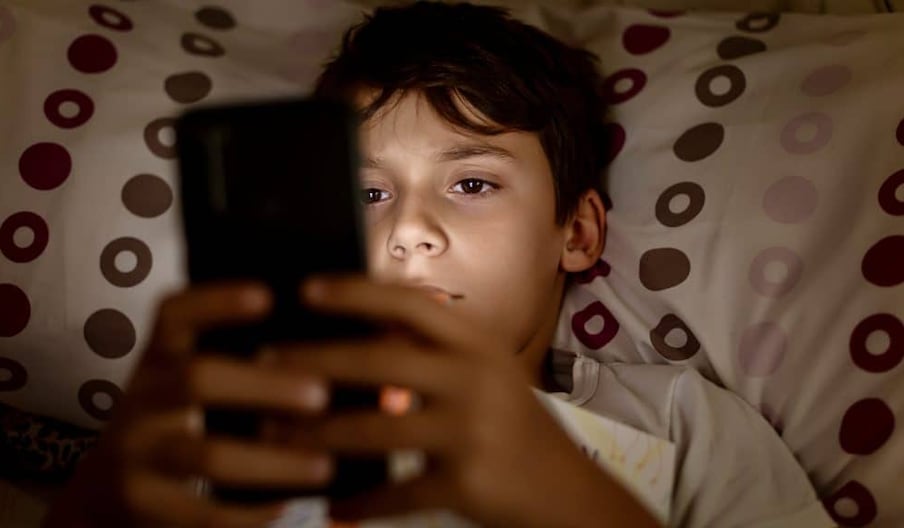 Un jeune adolescent sur son smartphone. Photographie d'illustration.