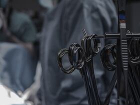 Instruments chirurgicaux, dans un bloc opératoire, alors qu'une équipe médicale est à l'œuvre.