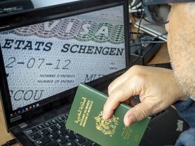 Un Marocain tient son passeport devant son ordinateur affichant un visa Schengen dans la capitale Rabat, le 28 septembre 2021.