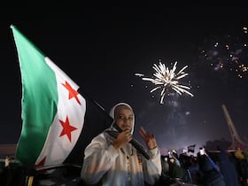 Une jeune femme brandit le drapeau syrien alors que les gens célèbrent le Nouvel An près de la place des Omeyyades à Damas, en Syrie, le 1er janvier 2025