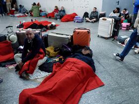 Des voyageurs, recouverts de couvertures de la Croix-Rouge, gisent à même le sol, se préparant à passer la nuit à la gare d'Atocha, à Madrid, le 28 avril 2025, suite à une panne de courant massive touchant toute la péninsule ibérique et le sud de la France