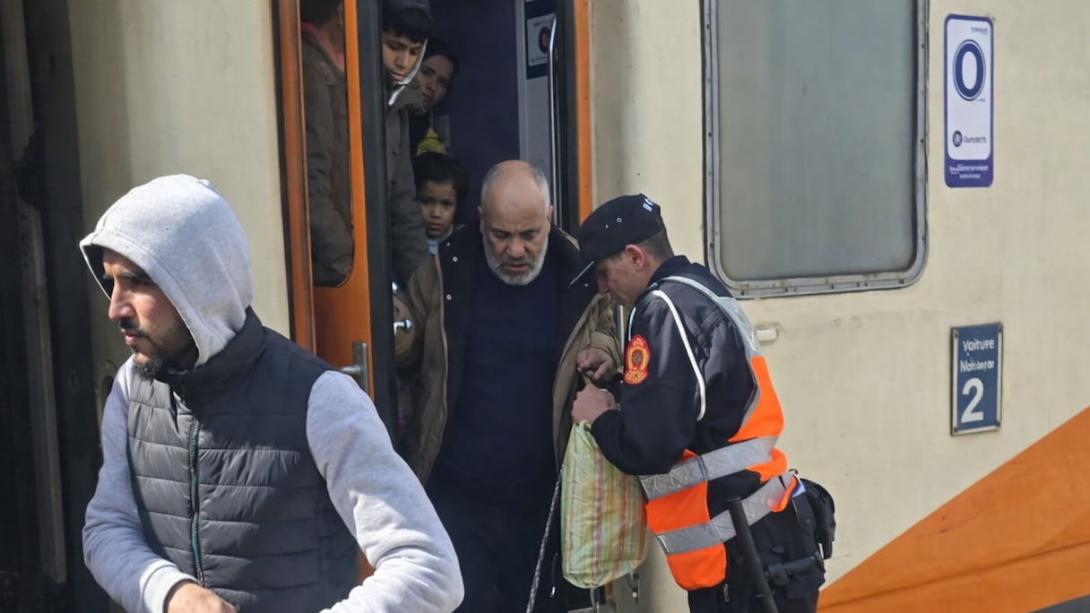 Un élément de la DGSN porte assistance à un passager à son arrivée à Ksar El Kébir, dimanche 15 février 2026, dans le cadre du retour des familles évacuées suite aux inondations.