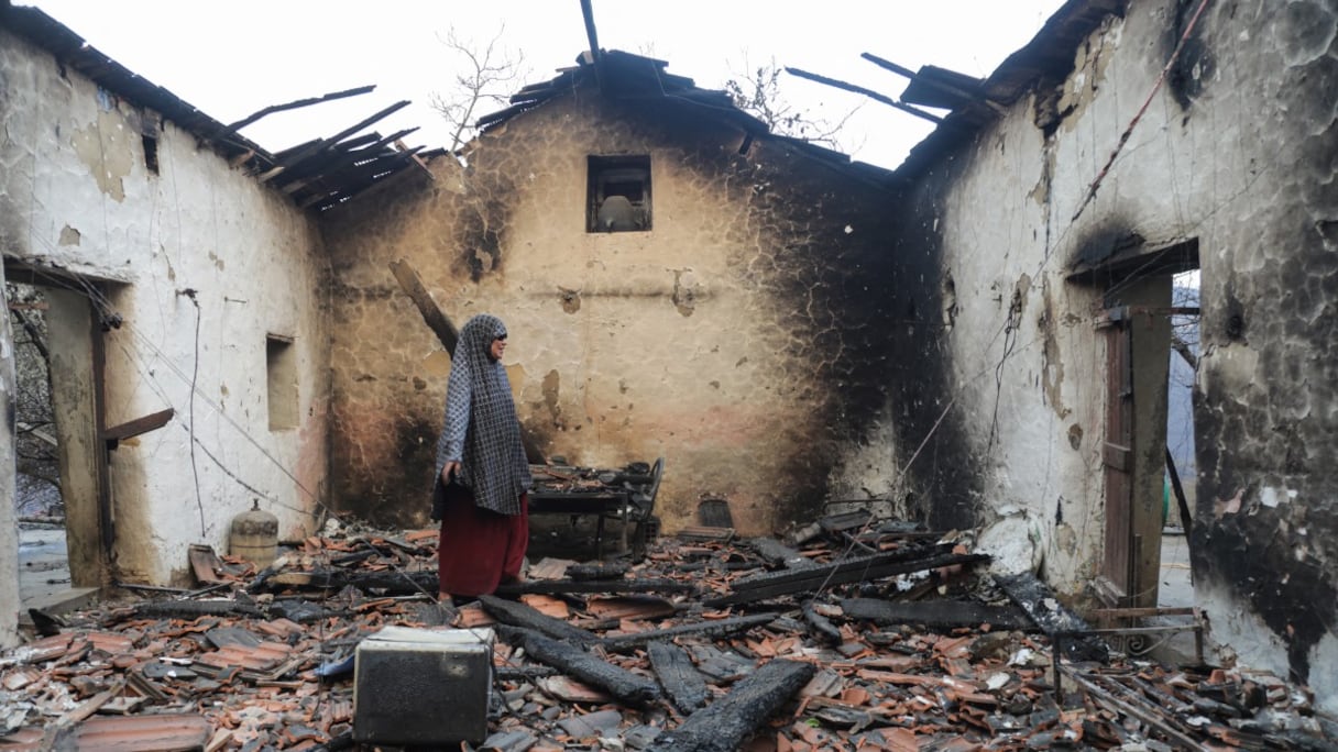Une femme inspecte sa maison endommagée après qu'elle a été ravagée par un feu de forêt à Bordj T'har, une commune de la province de Jijel, dans le nord-est de l'Algérie, le 27 août 2026.