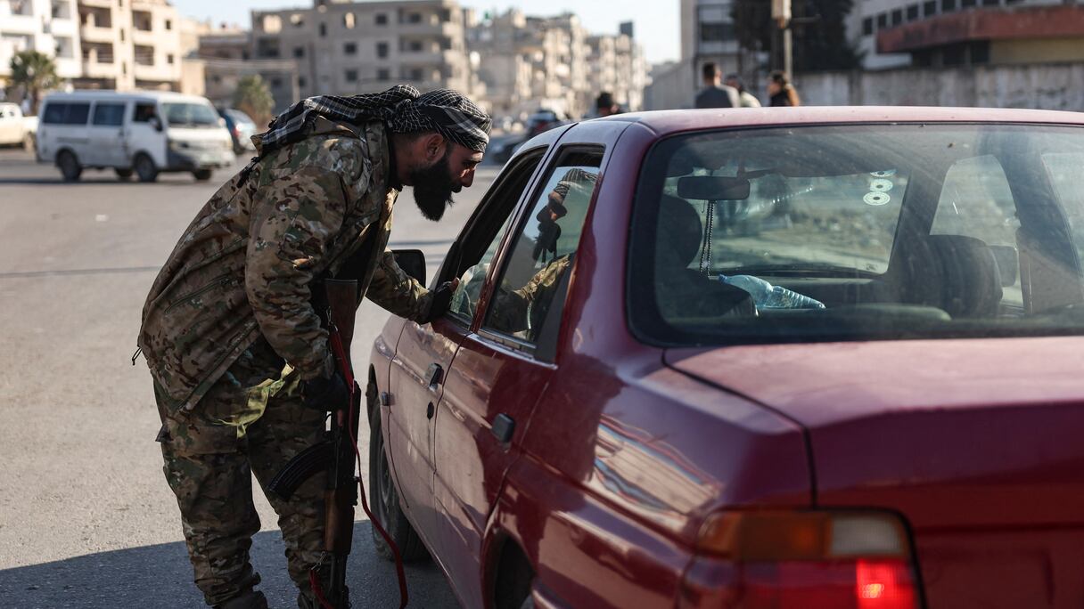 Un membre des forces de sécurité relevant du gouvernement intérimaire syrien vérifie l'identification d'un automobiliste à un point de contrôle à Homs, dans le centre-ouest de la Syrie, le 8 janvier 2025