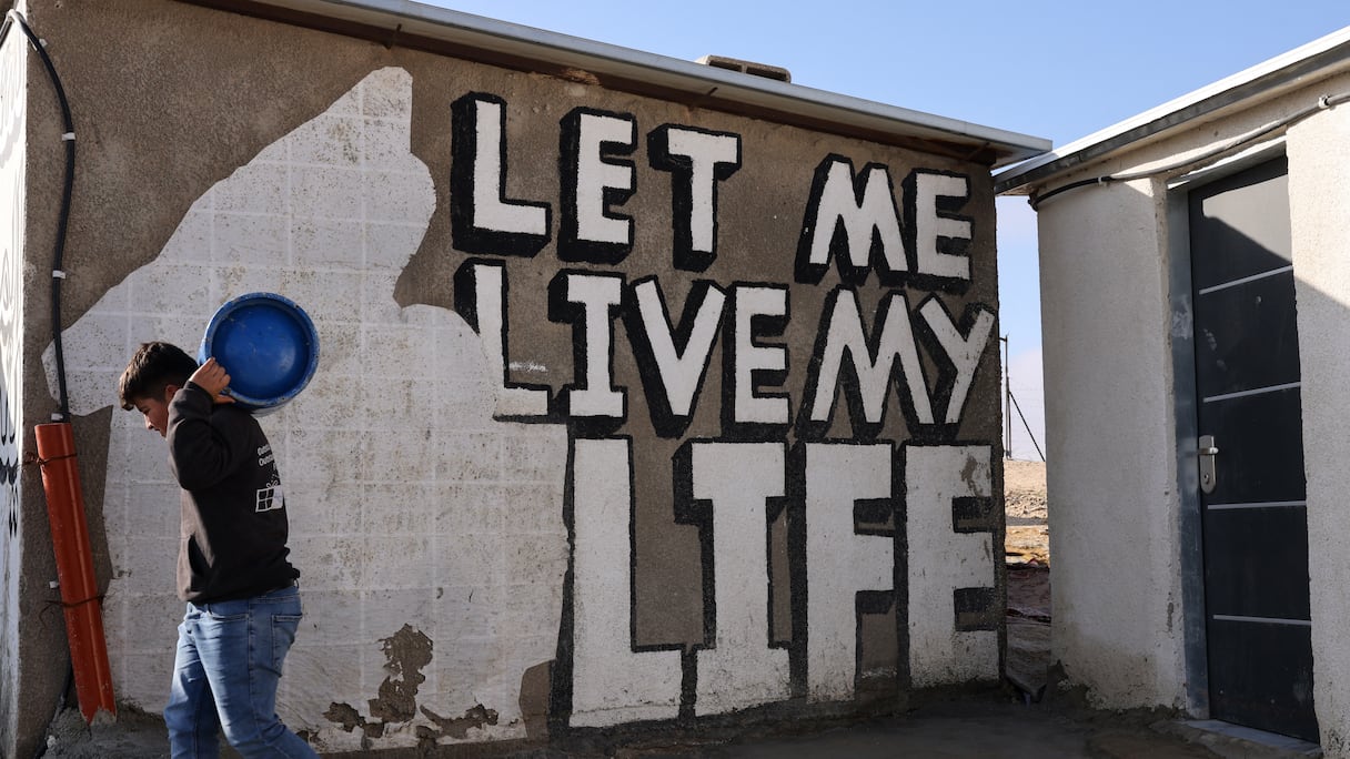 Un jeune Palestinien porte une bouteille de gaz dans le village de Khalet al-Daba'a, près de Yatta, dans le sud de la Cisjordanie occupée, après que les machines de l'armée israélienne ont démoli les structures et les zones d'habitation sur le site, le 13 février 2025