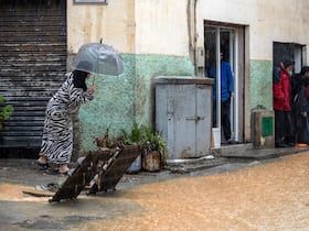 Des personnes s'abritent de la pluie dans une rue inondée par temps orageux à Fnideq, dans le nord du Maroc, le 5 mars 2021.