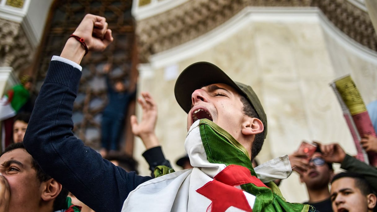 Un jeune homme, le bras levé, au milieu de la foule, lors d'une manifestation du Hirak algérien dans la capitale Alger.