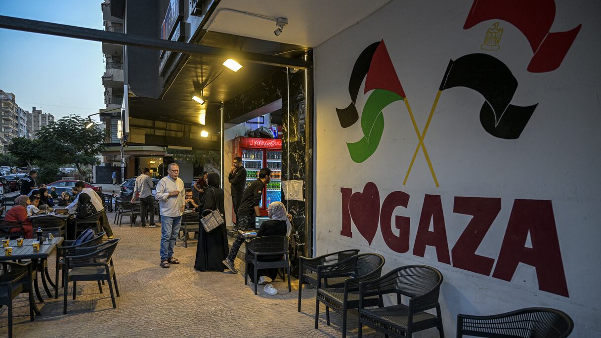 Le propriétaire du restaurant palestinien Bassem Abu Aoun s'adresse à un client devant l'établissement «Hay Al-Rimal», du nom de son quartier de la ville de Gaza, au Caire, le 28 octobre 2024