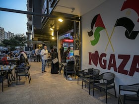 Le propriétaire du restaurant palestinien Bassem Abu Aoun s'adresse à un client devant l'établissement «Hay Al-Rimal», du nom de son quartier de la ville de Gaza, au Caire, le 28 octobre 2024