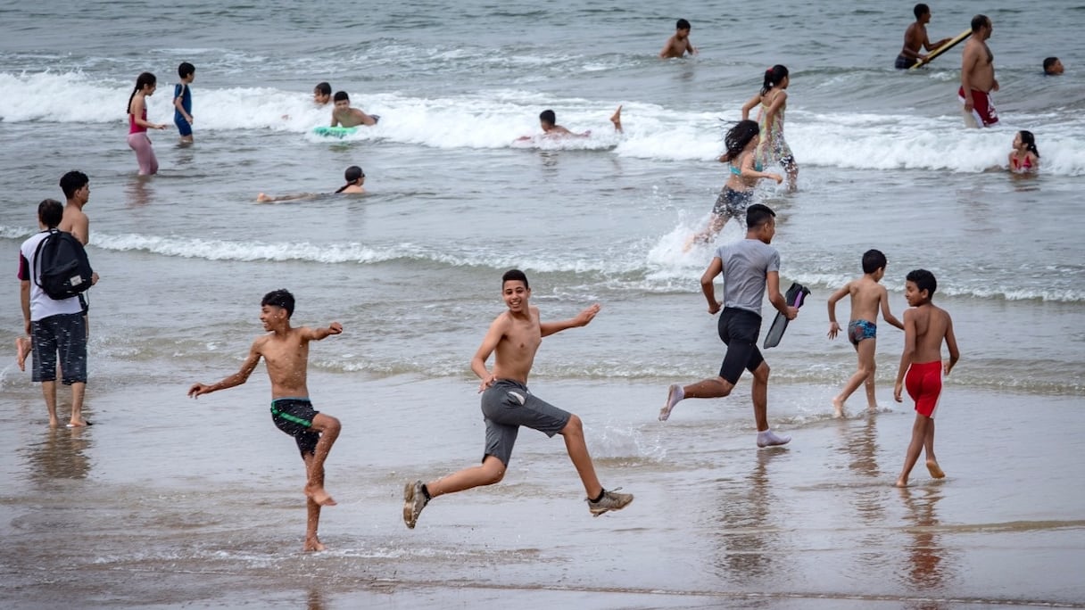 De jeunes baigneurs s'amusent sur une plage le long de la côte de la ville de Salé, au nord de Rabat, le 25 juin 2020.