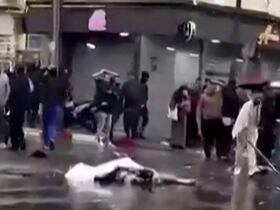 Une capture vidéo à partir d'images publiées sur les réseaux sociaux le 13 avril 2026, montrant des passants debout près d'un corps recouvert gisant au milieu d'une rue à Blida.
