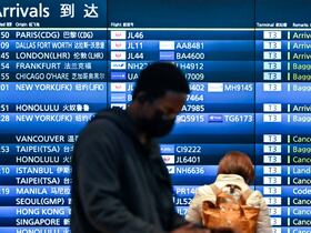 Des gens se tiennent devant le panneau des arrivées montrant des vols annulés à l'aéroport international Haneda de Tokyo, le 30 novembre 2021.