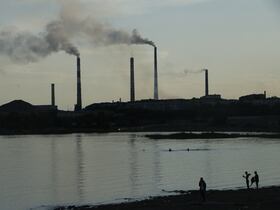 Des habitants profitent du lac Balkhash dans la ville de Balkhash, avec la fonderie de cuivre Kazakhmys en arrière-plan, le 18 juin 2024