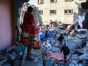 Un jeune homme enveloppé dans une couverture regarde les gens chercher des survivants dans les décombres d'un bâtiment touché par une frappe israélienne dans le camp de réfugiés palestiniens de Bureij, dans le centre de la bande de Gaza, le 2 mai 2025