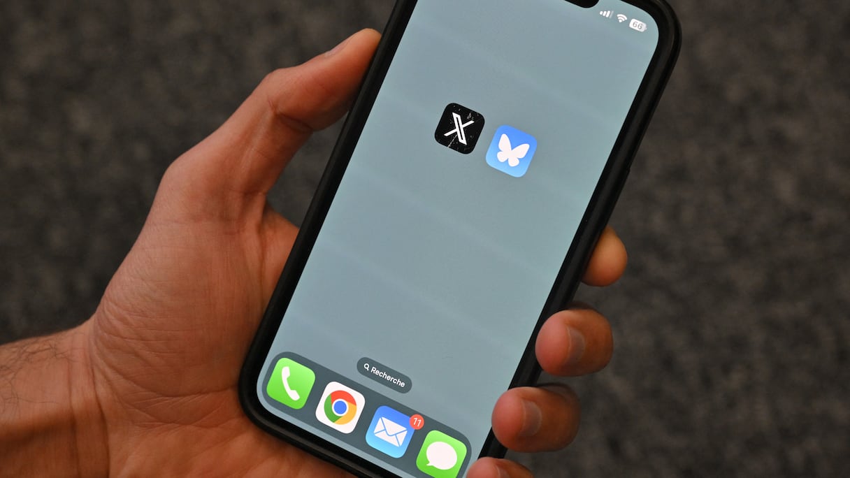 Cette photographie d'illustration prise à Bruxelles le 18 novembre 2024 montre les logos du réseau social américain X (ancien Twitter) (à gauche) et Bluesky affichés sur un téléphone portable.