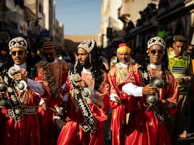Une troupe traditionnelle gnaoua défile dans les rues lors de la cérémonie d'ouverture de la 25e édition du Festival Gnaoua et Musiques du Monde à Essaouira, au Maroc, le 27 juin 2024.