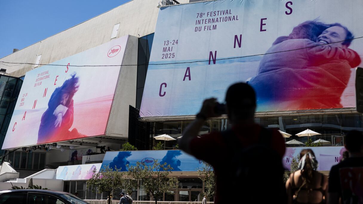 Un piéton prend une photo des affiches de la 78e édition du Festival de Cannes devant le Palais des Festivals, le 12 mai 2025