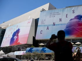 Un piéton prend une photo des affiches de la 78e édition du Festival de Cannes devant le Palais des Festivals, le 12 mai 2025