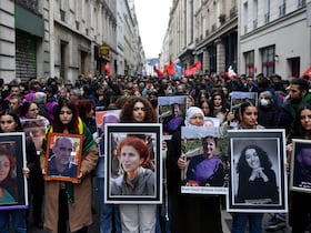 Des manifestants tiennent les portraits des victimes de la fusillade de la rue d'Enghien à Paris le 23 décembre 2022, et de celles des meurtres de la rue La Fayette en 2013, lors d'une marche pour leur rendre hommage et en solidarité avec la communauté kurde de Paris, le 26 décembre 2022.