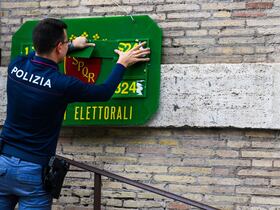 Un policier installe un panneau d'identification officiel le 24 septembre 2022 devant un bureau de vote à Rome, à la veille des élections législatives du pays.