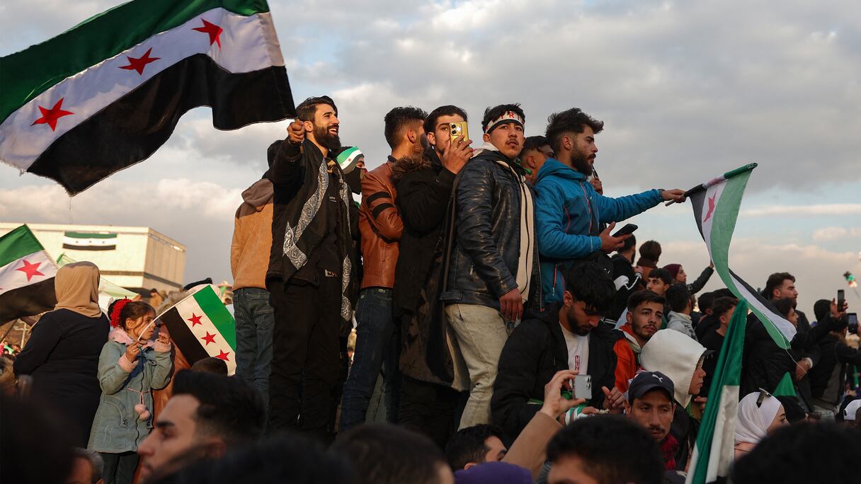 Des gens brandissent des drapeaux syriens de l'ère de l'indépendance lors des célébrations de l'éviction du président Bashar al-Assad sur la place principale des Omeyyades à Damas, la capitale, le 20 décembre 2024