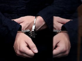 Un homme menotté est conduit au tribunal.