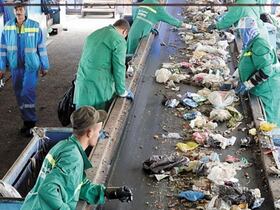 Plusieurs agents triant des déchets ménagers sur un tapis convoyeur.