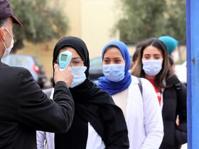 Un agent de sécurité prend la température des élèves à l'entrée du lycée secondaire qualifiant Hassan II, le 11 janvier 2022, à Marrakech, afin de faire détecter d'éventuels cas de Covid-19.