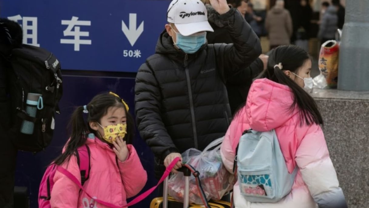 Un homme et ses deux filles, portant un masque de protection, arrivent à la gare de Pékin pour se rendre dans leur famille à l'occasion du Nouvel An chinois, le 21 janvier 2020.
