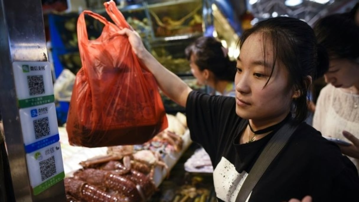 Une femme regarde les codes QR utilisés pour la numérisation des paiements sur un marché à Pékin, le 27 juin 2017. 
