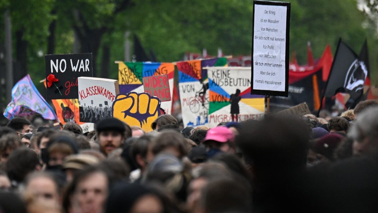 Des manifestants brandissent des drapeaux et des pancartes lors d'une manifestation pour la fête du Travail, dans le quartier de Neukoelln, à Berlin, le 1er mai 2022.
