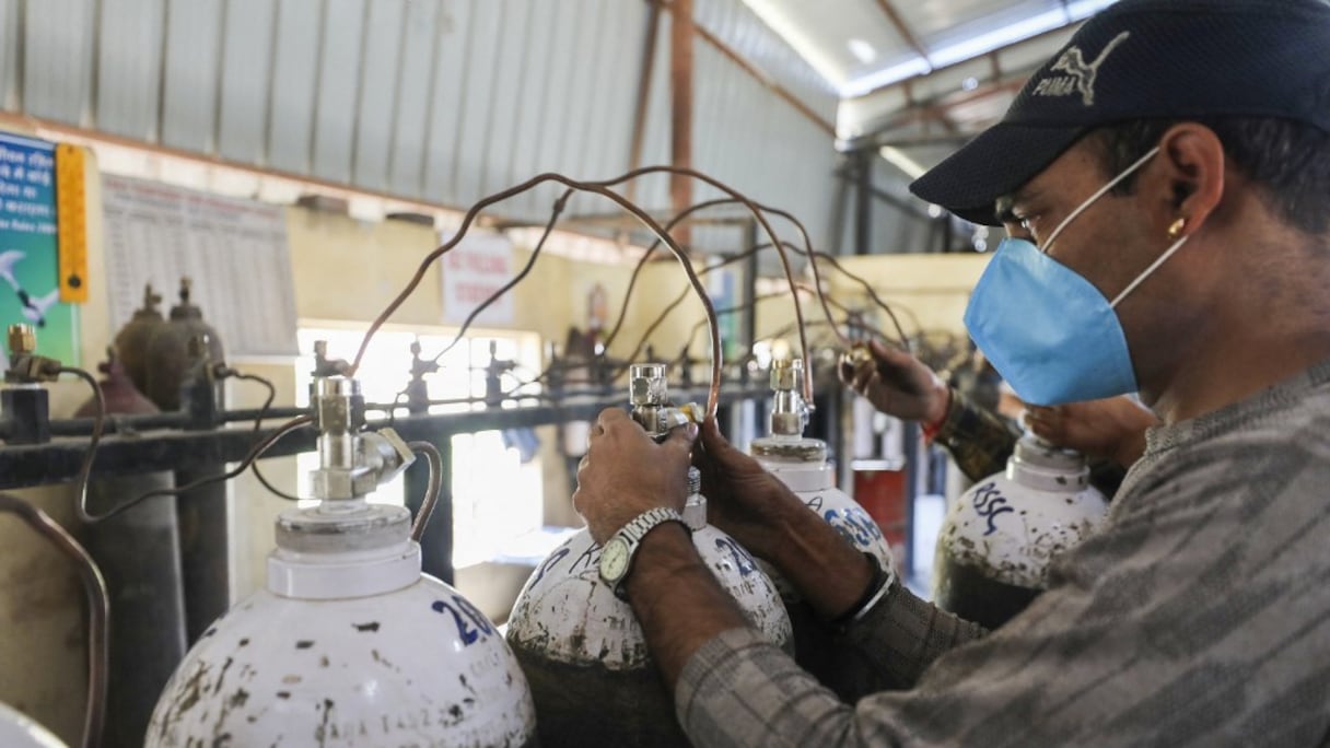 Des travailleurs remplissent des bouteilles d'oxygène médical pour fournir aux hôpitaux le traitement du Covid-19 dans un établissement à la périphérie de Jammu, le 23 avril 2021. 
