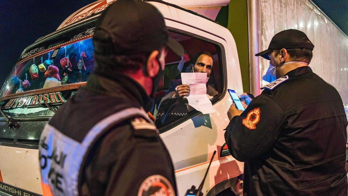 Des policiers contrôlent le laisser-passer d'un chauffeur routier pendant le couvre-feu le 2 mai 2020 à Rabat. 
