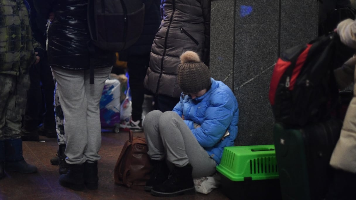 Une femme dort, assise au sol, à côté de sa cage de transport pour chat, à la gare centrale de Lviv, dans l'ouest de l'Ukraine, le 26 février 2022.
