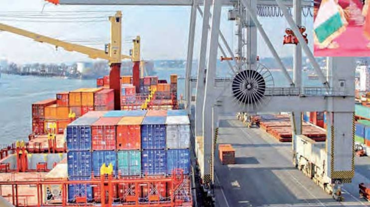 Des containers et un pont de grue au sein d'une installation portuaire.
