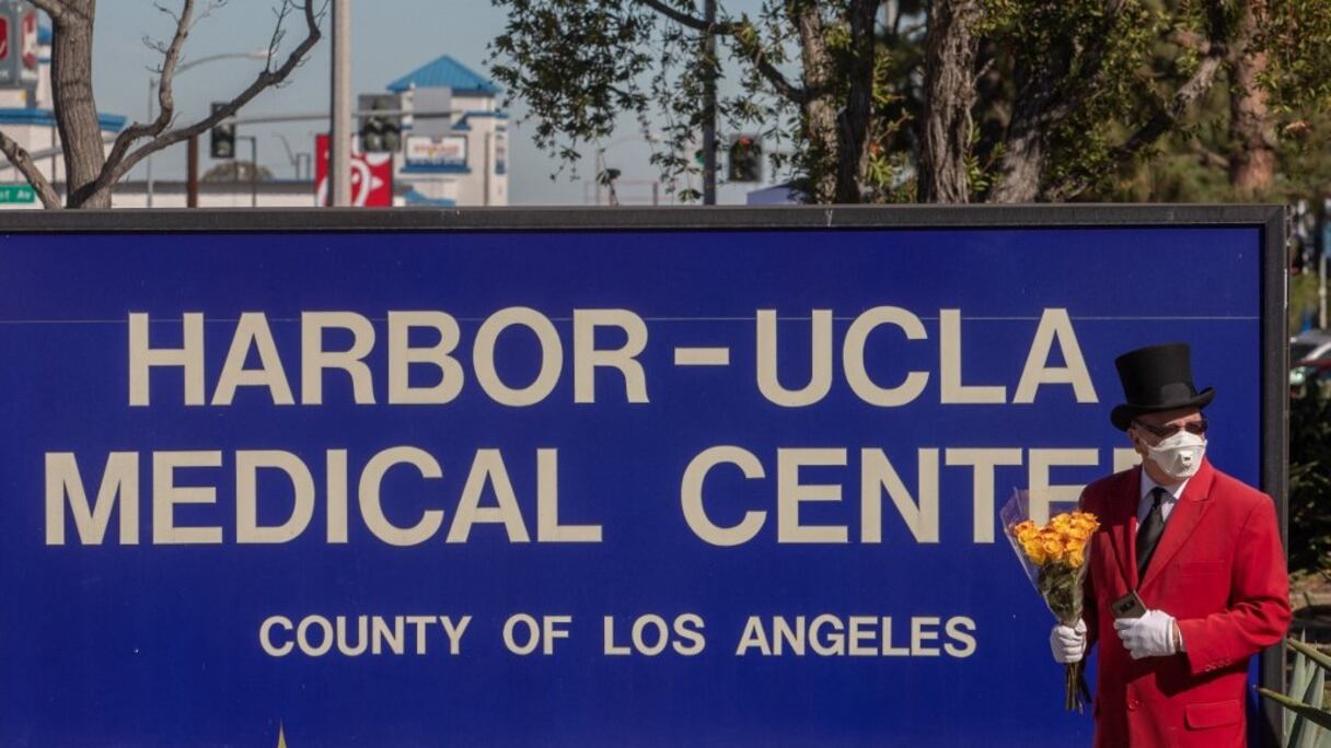 Un fan de Tiger Woods, Gregg Donovan, tenant des fleurs, se tient devant l'entrée principale du centre médical du port UCLA à Torrance, en Californie, le 23 février 2021, où la star américaine du golf est hospitalisée après un accident de voiture à Palos Verdes.