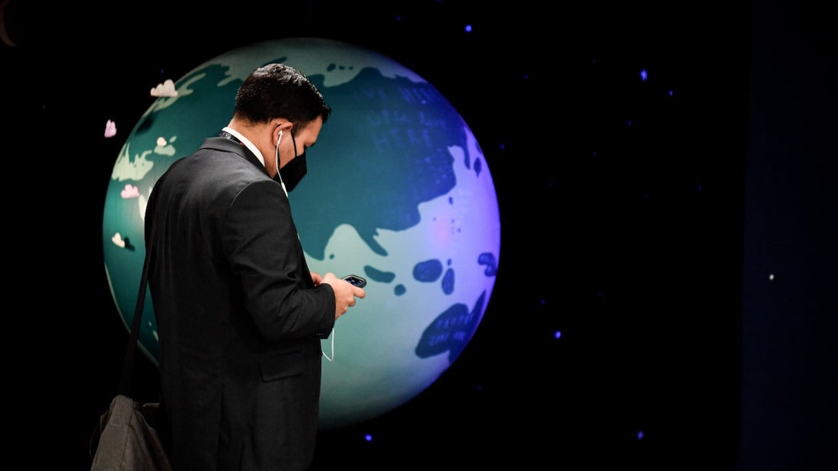 Un homme devant un globe terrestre, au premier jour de la COP26 au Scottish Event Campus (SEC) à Glasgow, en Ecosse, le 31 octobre 2021. Jusqu'au 12 novembre, les Etats tenteront de fixer des objectifs d'émissions mondiaux pour ralentir le réchauffement climatique.
