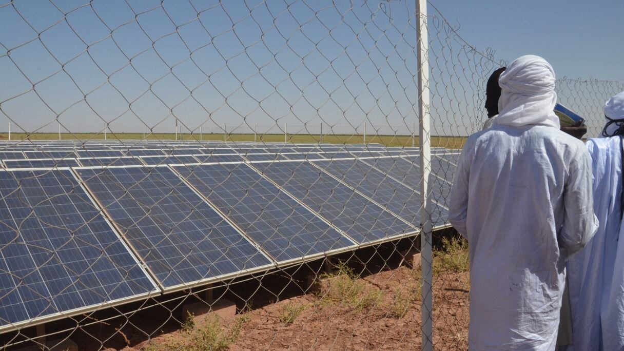 Des hommes régénèrent des panneaux solaires qui pompent l'eau du forage, pour irriguer le site du projet Irhazer, financé par la France près d'Agadez, dans le nord du désert du Niger, le 8 novembre 2019.
