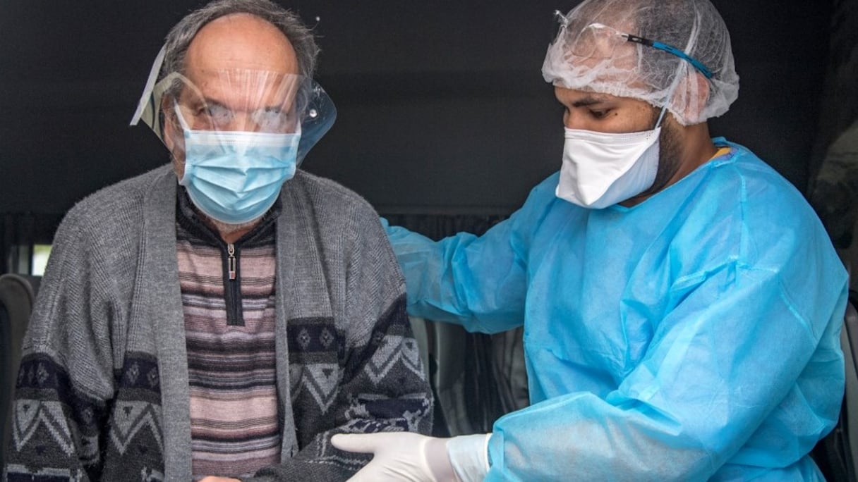 Un membre de l'équipe médicale de l'hôpital Prince Moulay Abdellah de Salé accompagne un patient guéri du Covid-19 à la sortie de cet établissement. 
