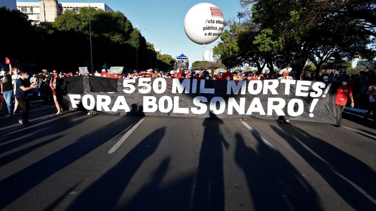 Des manifestants tiennent une banderole indiquant "550 000 morts. Bolsonaro dehors!", lors d'une manifestation contre le gouvernement du président brésilien Jair Bolsonaro, à Brasilia, le 24 juillet 2021.
