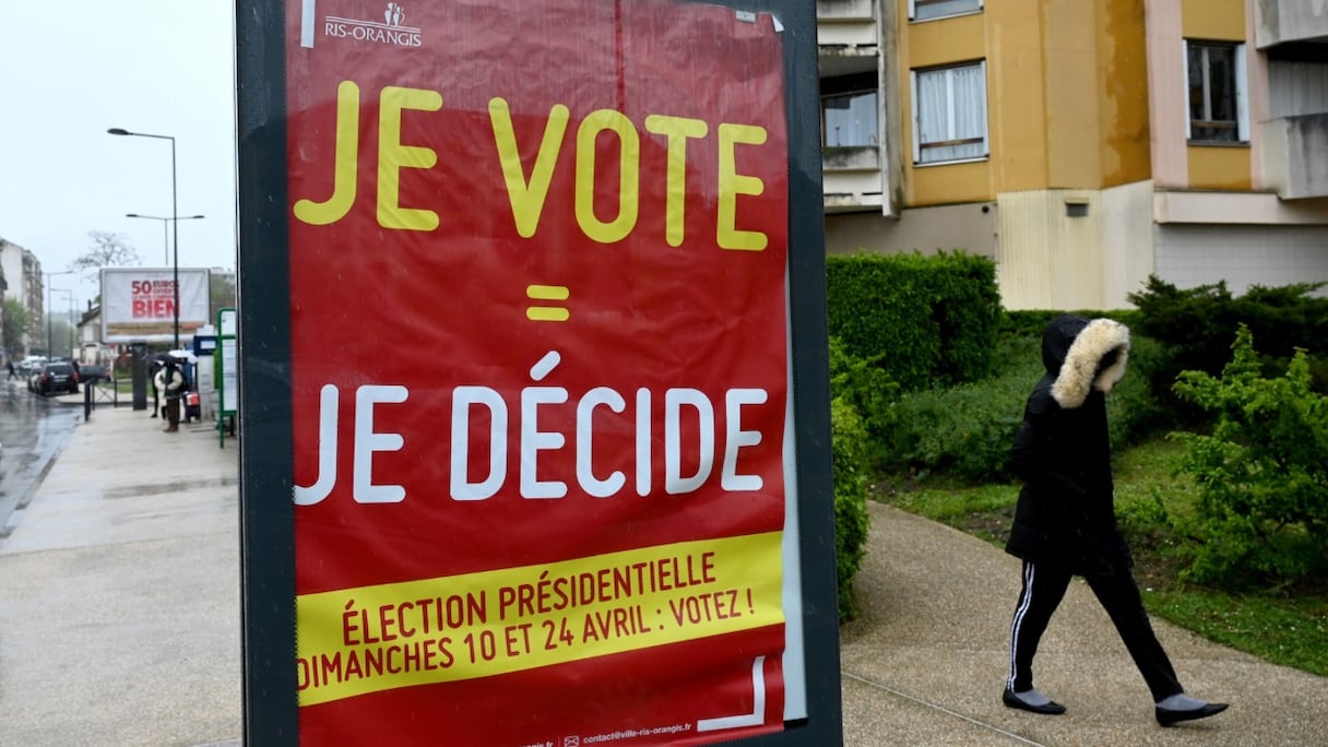 Un piéton passe devant une affiche appelant à voter lors de l'élection présidentielle française, dans la banlieue parisienne de Ris-Orangis, le 8 avril 2022.
