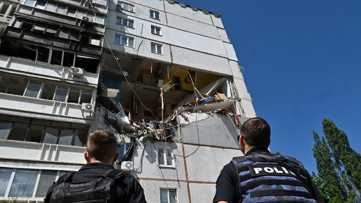 Des policiers ukrainiens regardent un bâtiment partiellement détruit à la suite d'un bombardement à Kharkiv, le 16 juin 2022, alors que la guerre russo-ukrainienne entre dans son 113e jour.
