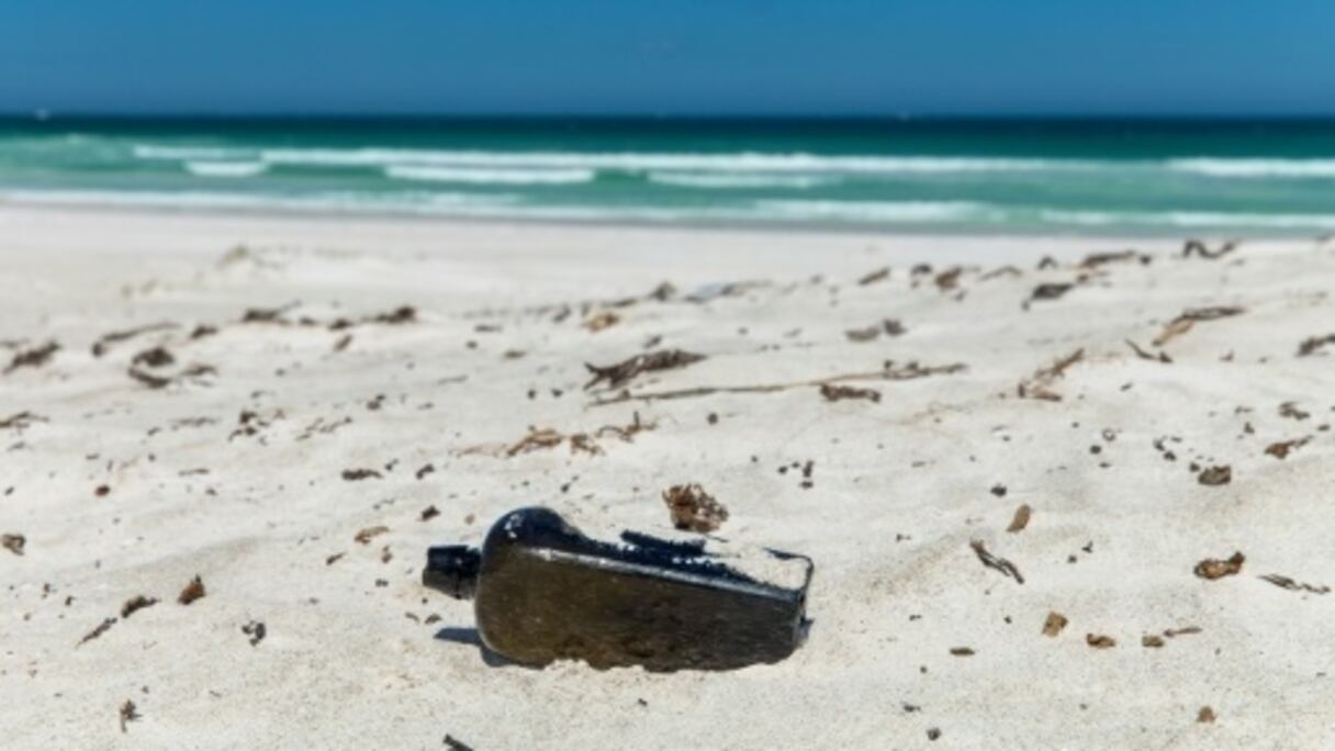 La bouteille rectangulaire était à moitié enfouie dans le sable.