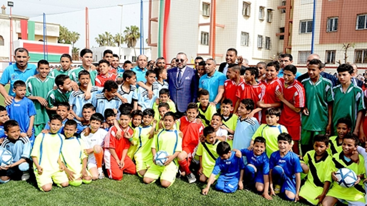 Le souverain entouré de jeunes lors de l'inauguration du stade de proximité ce 30 mars à Casablanca.
