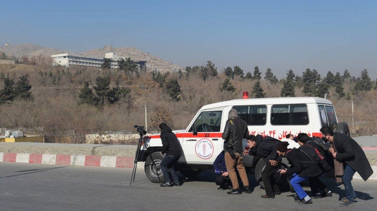 Des journalistes afghans se réfugient derrière une ambulance pendant les combats dans l'hôtel Intercontinental de Kaboul, le 21 janvier 2018.
